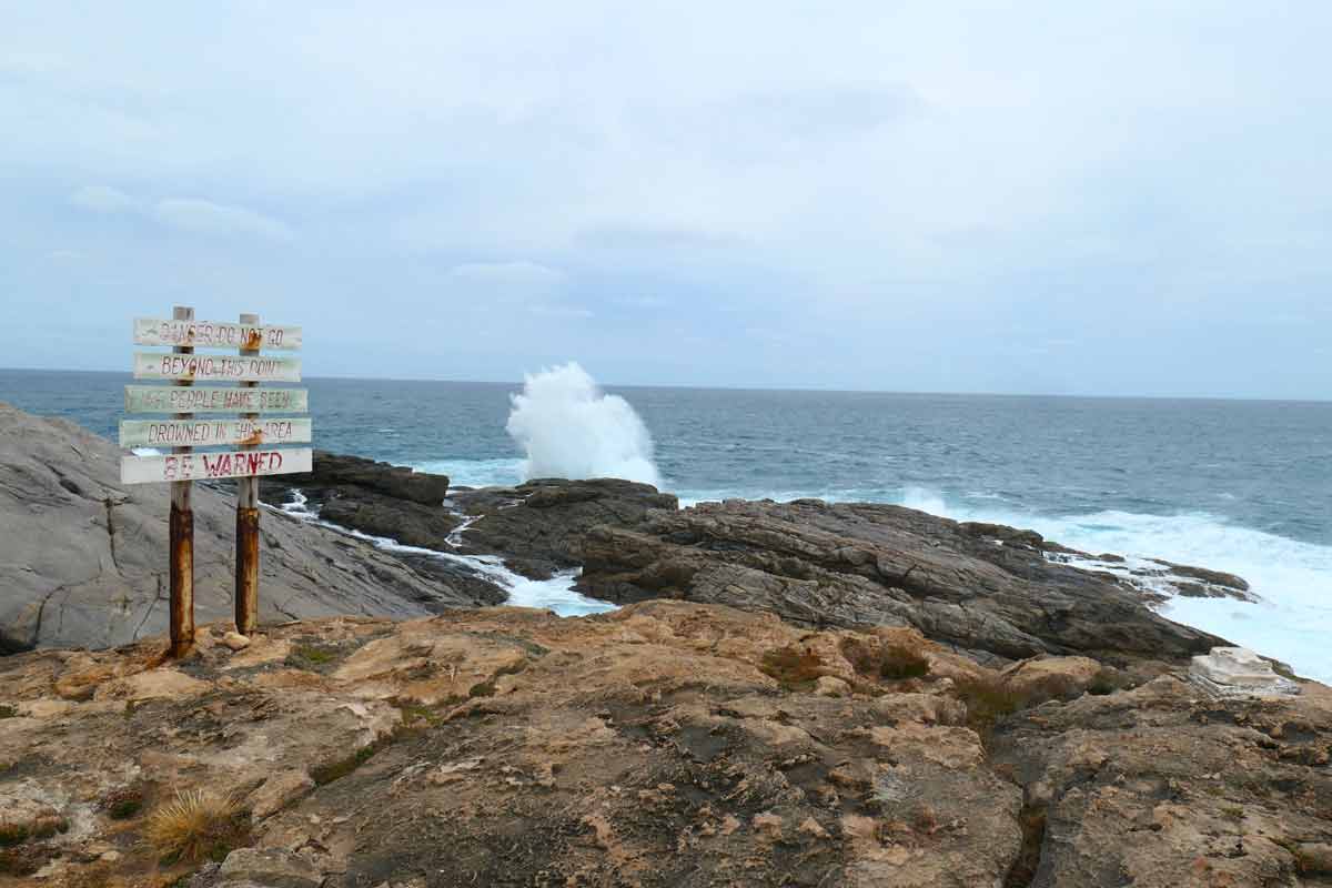 Cape Carnot dange sign with wave crashing. Located in Whaler's Way Sanctuary, Eyre Peninsula, South Australia.